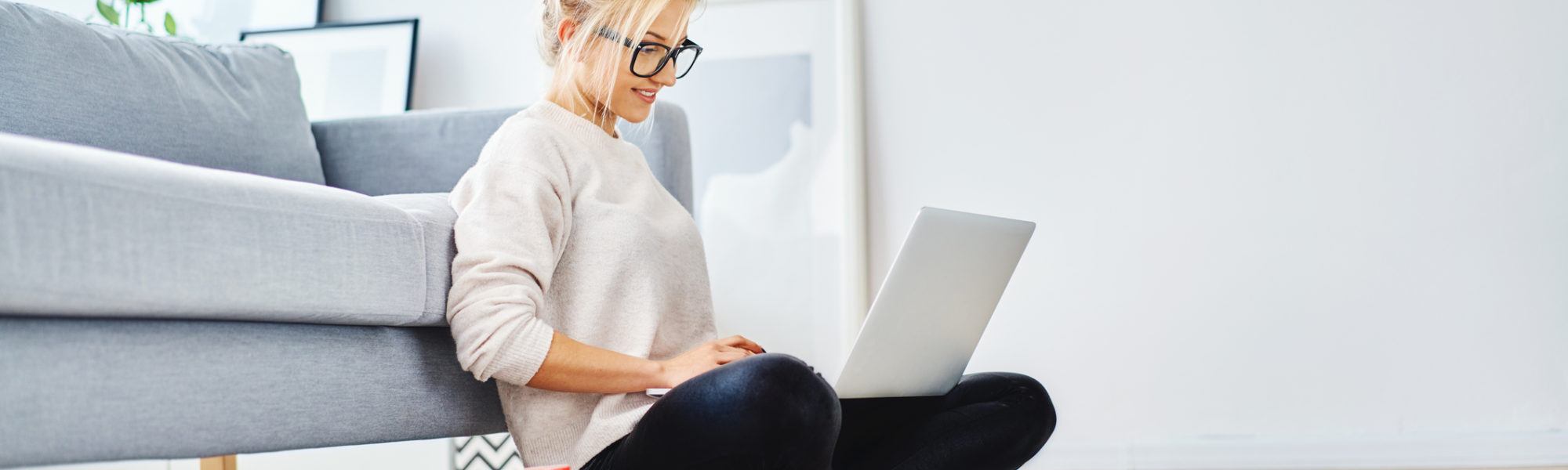 Female student sitting on floor of her apartment with laptop and notes studying