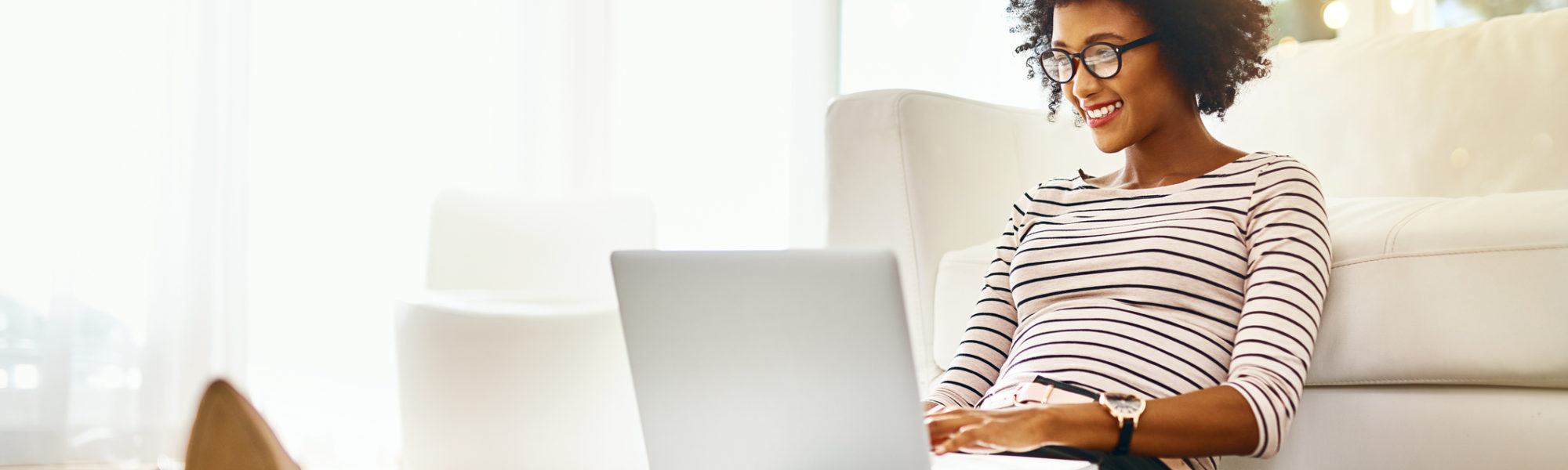 smiling woman sitting on the ground and working on her laptop