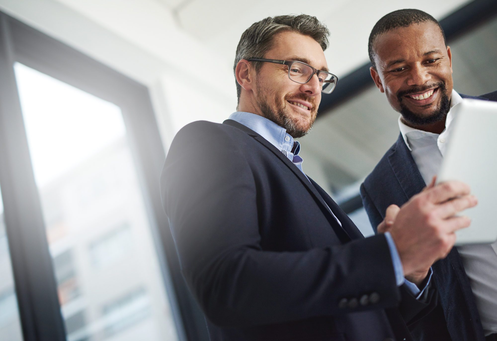 Two men in suits looking at a tablet
