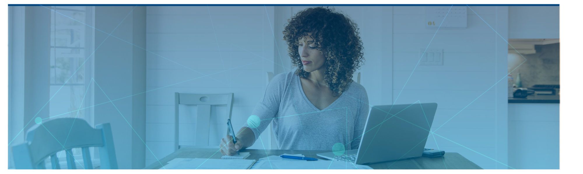woman signing paper work while working on her laptop