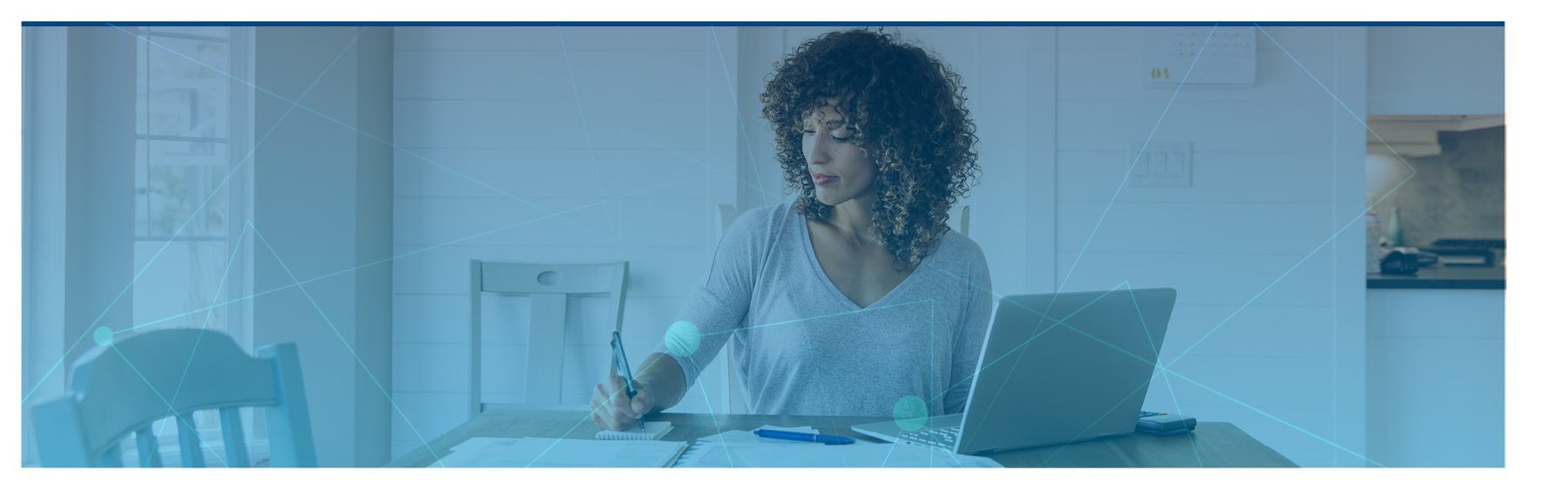 woman signing paper work while working on her laptop