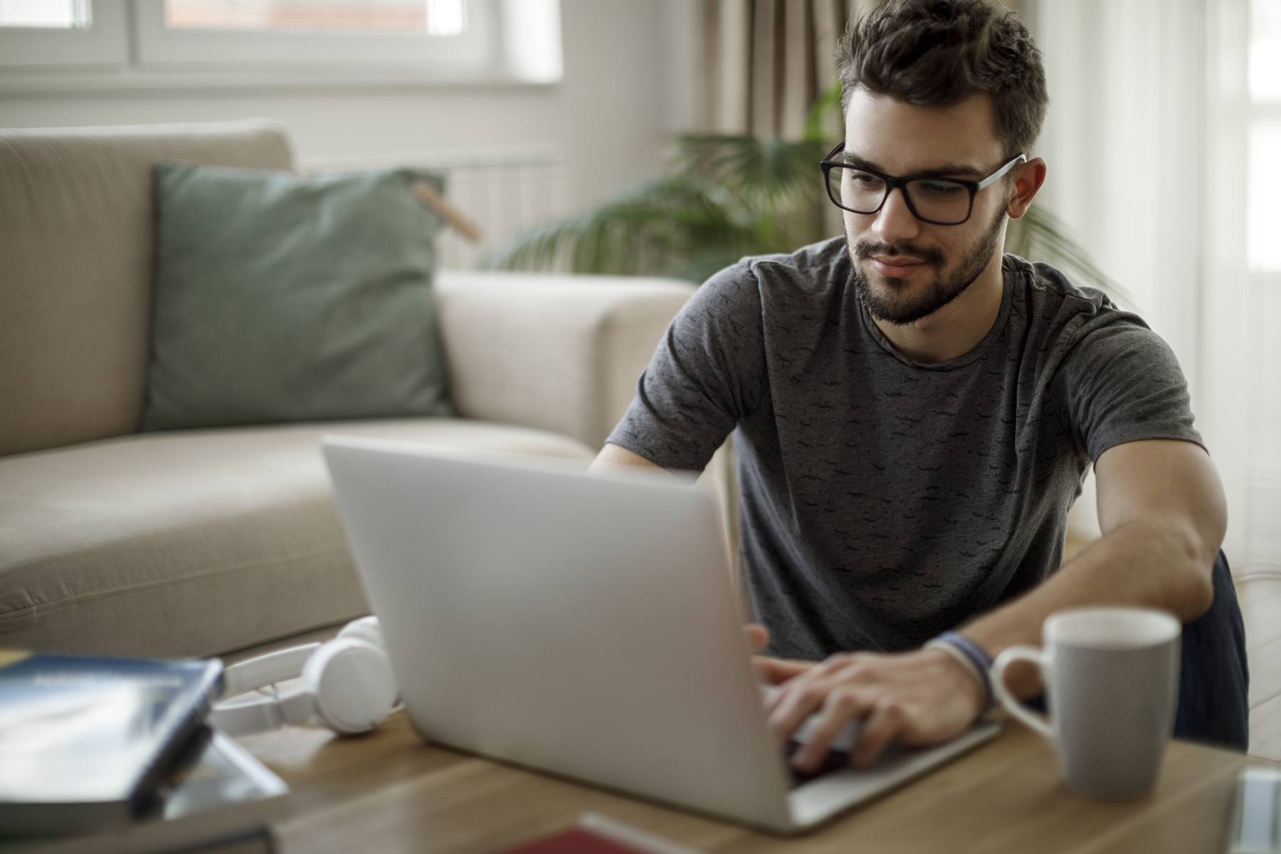 man with glasses works on his laptop at home