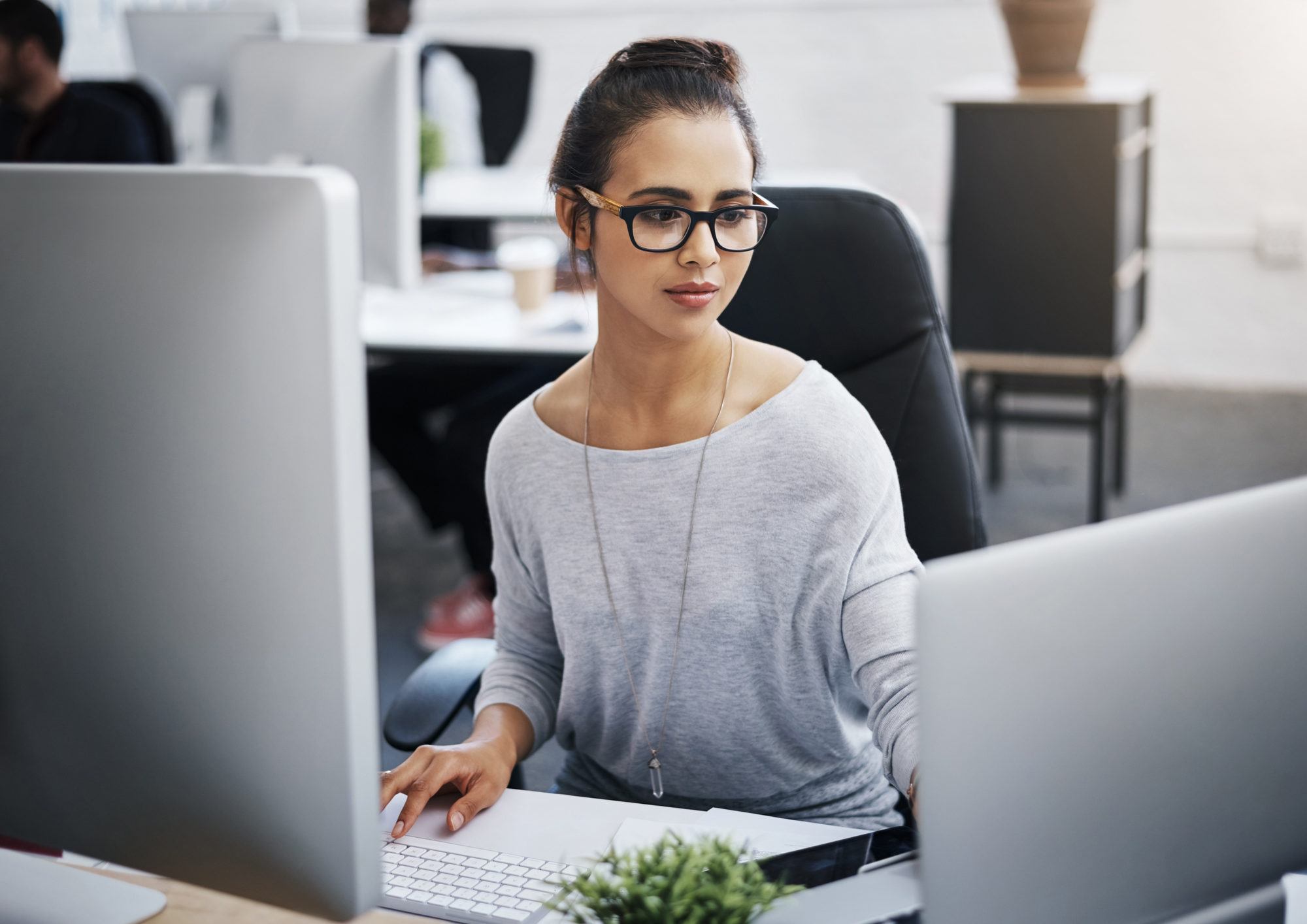 businesswoman with glasses working on her computer and laptop