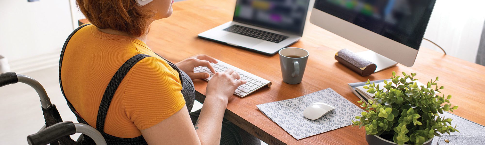 programmer in wheelchair working on her laptop and computer