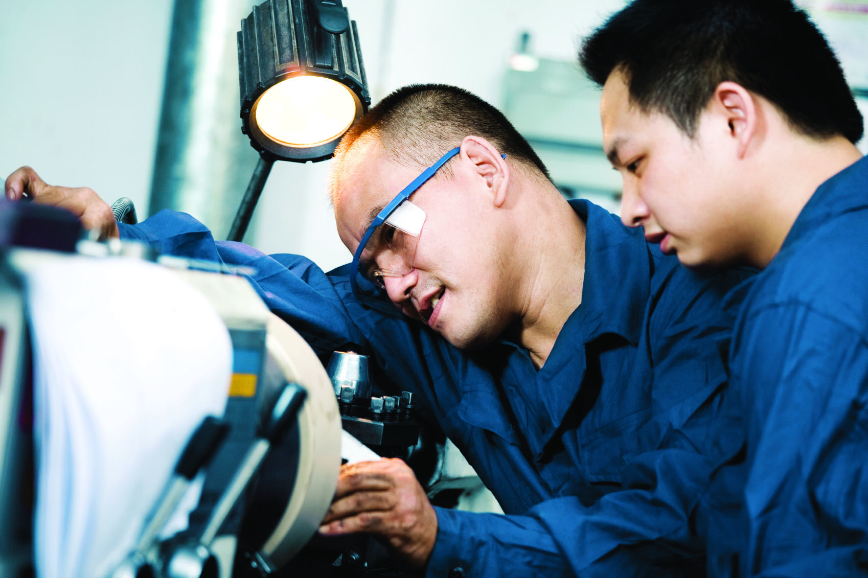 engineer training young man while working on machinery