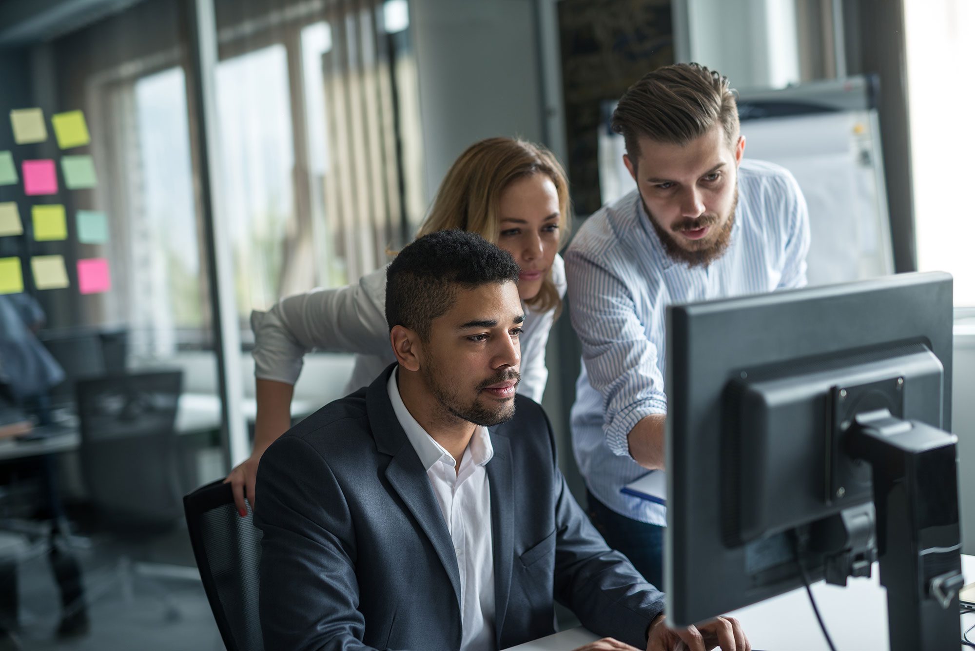 Three people working on a project together at a computer