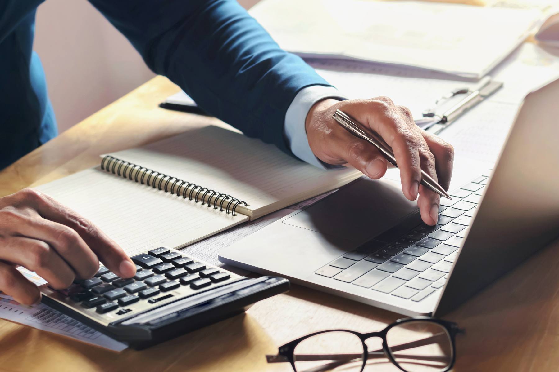 businessman typing on his laptop with one hand and typing on calculator with the other hand
