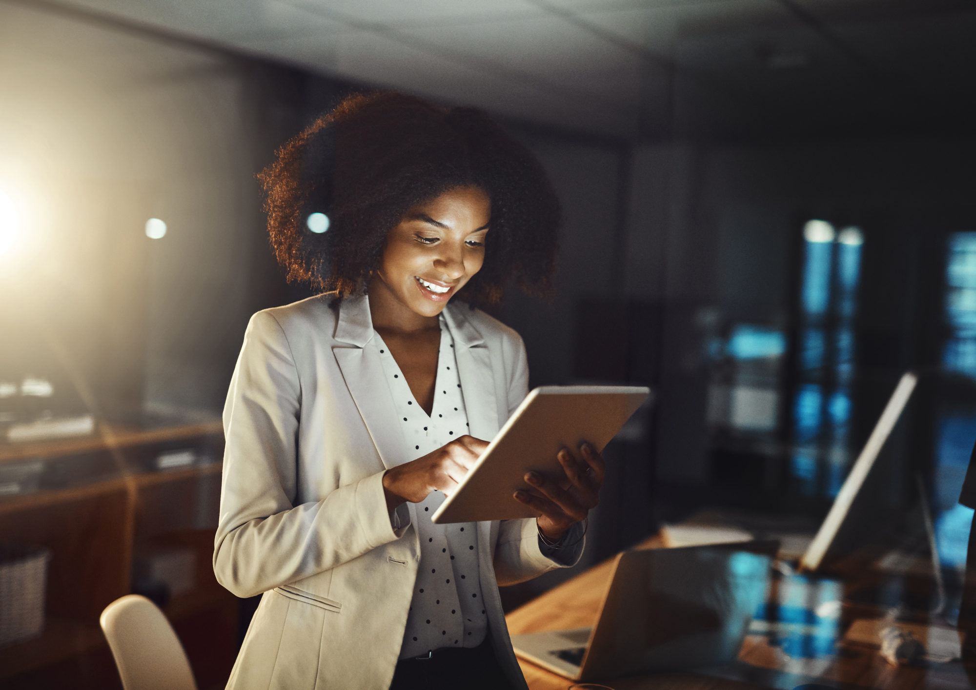 A professional woman looking at her tablet while smiling