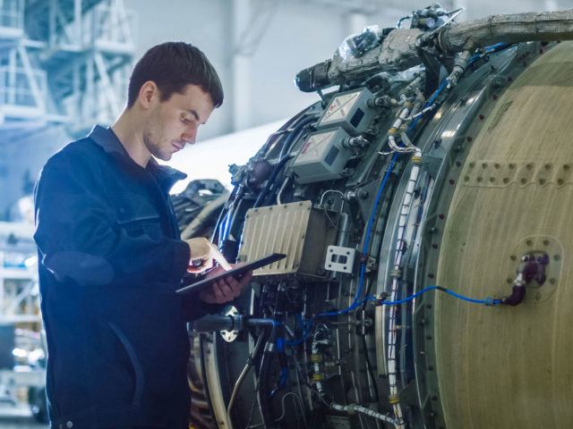 aerospace engineer using tablet working on engine