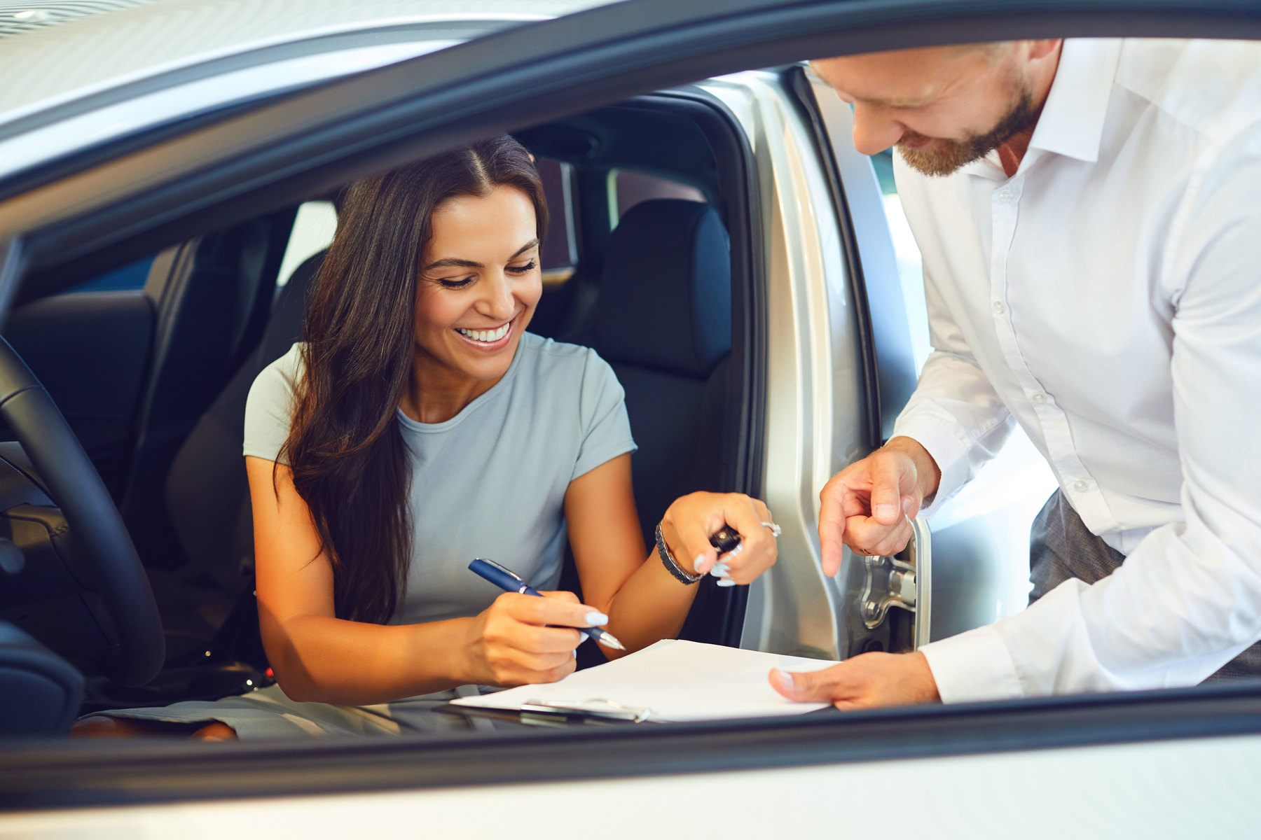 female signing papers to purchase new car