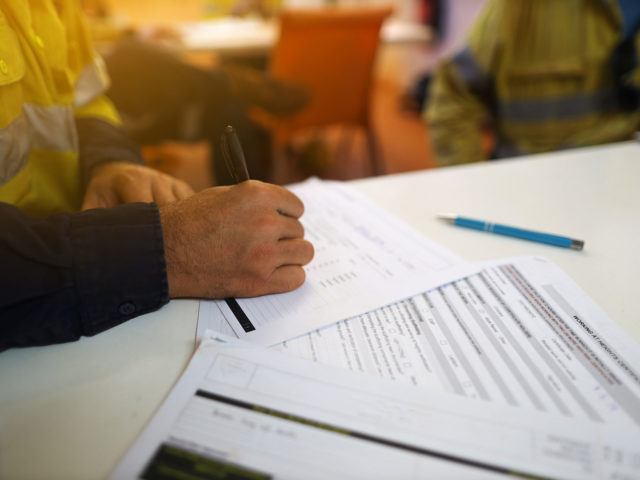 man filling paperwork out with black pen