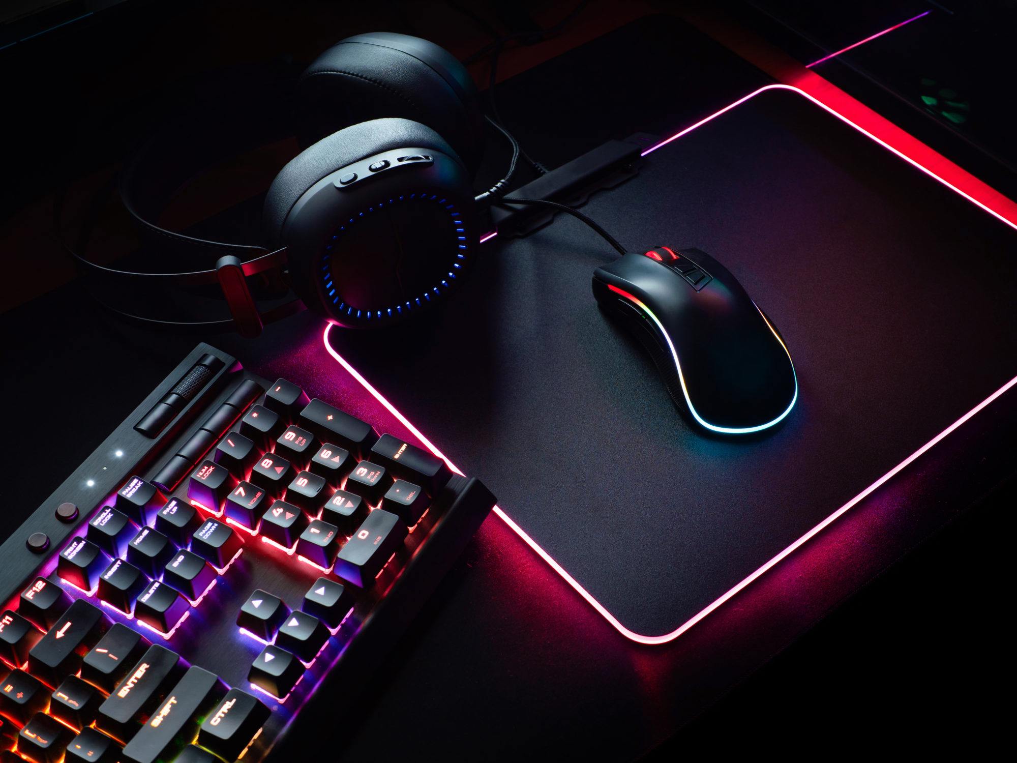 Blick von oben auf eine Gaming-Maus, eine Tastatur in RGB-Farbe, Joystick, Headset, Webcam, VR-Headset