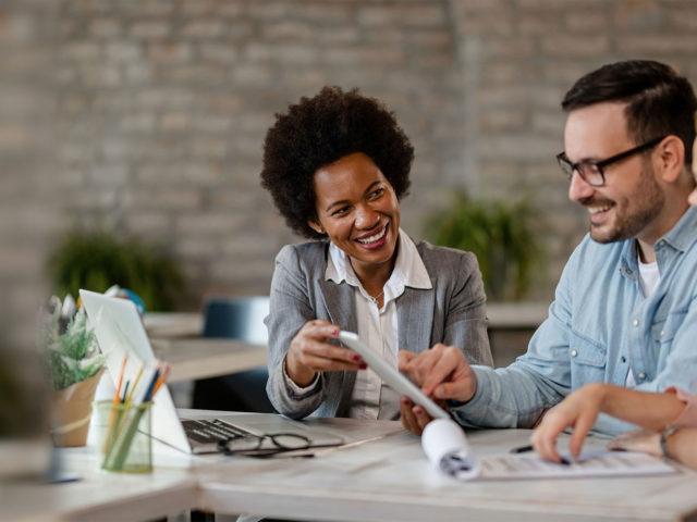 coworkers laughing at something in a digital tablet