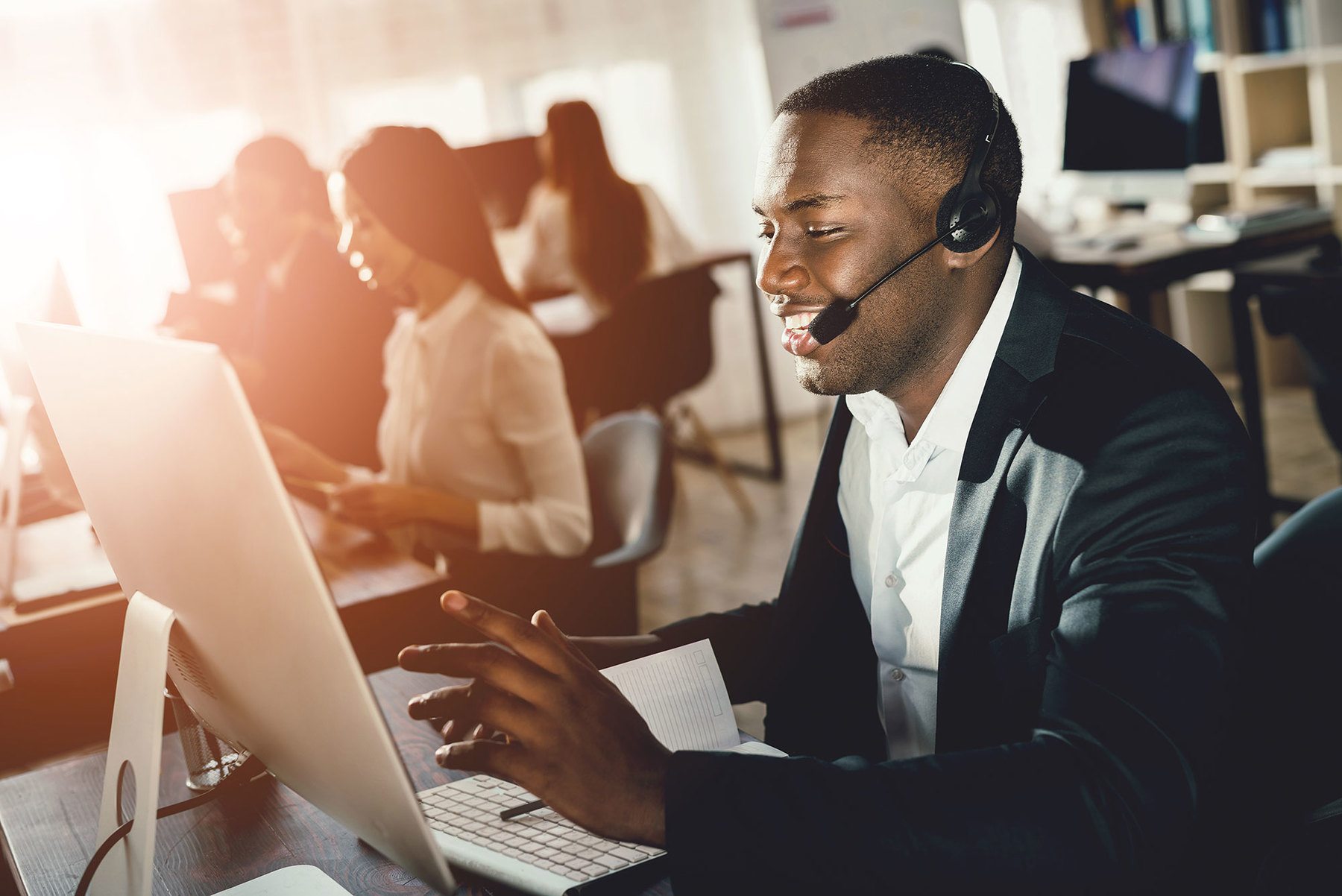 Call Center worker talking to headset while working on his computer