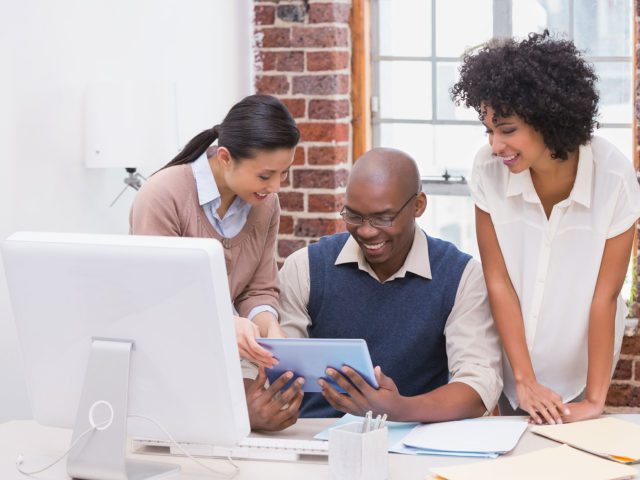 coworkers collaborating on digital tablet in office