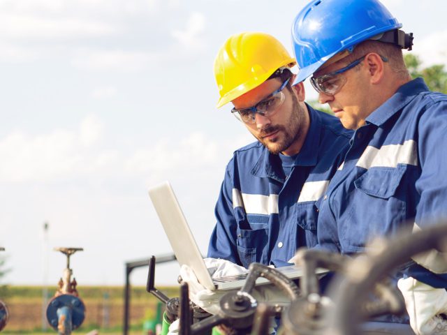 energy plant engineers working on laptop outside