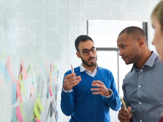 Portrait of an Indian man in a diverse team of creative millennial co-workers in a startup brainstorming strategies