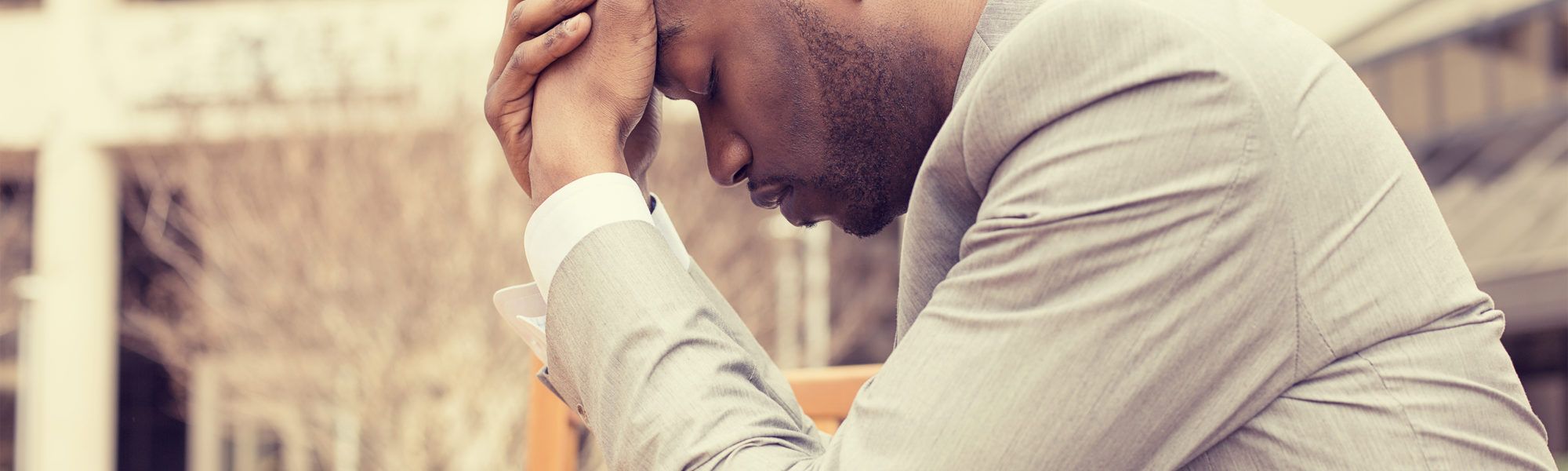 stressed young businessman sitting outside corporate office
