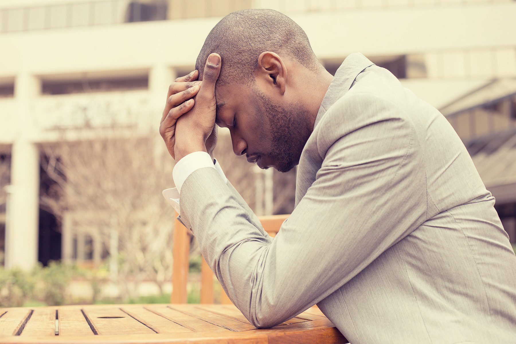 stressed young businessman sitting outside corporate office