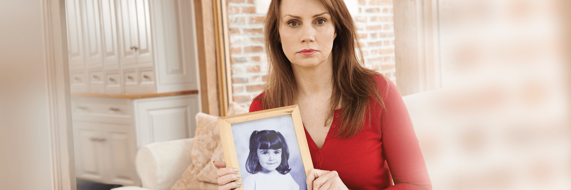 woman sitting and holding picture of herself as a baby
