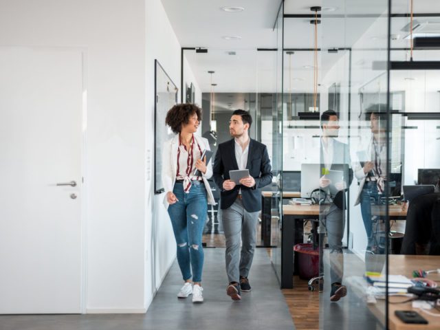 African businesswoman and her Caucasian coworkers using digital tablet and walking in the office