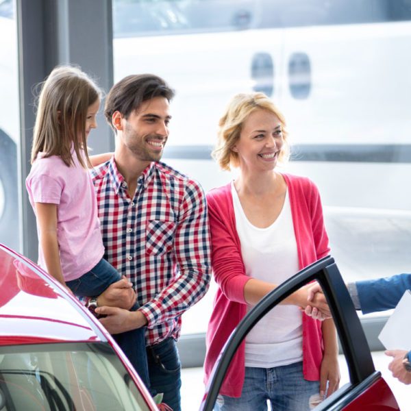 family at car dealership with salesman