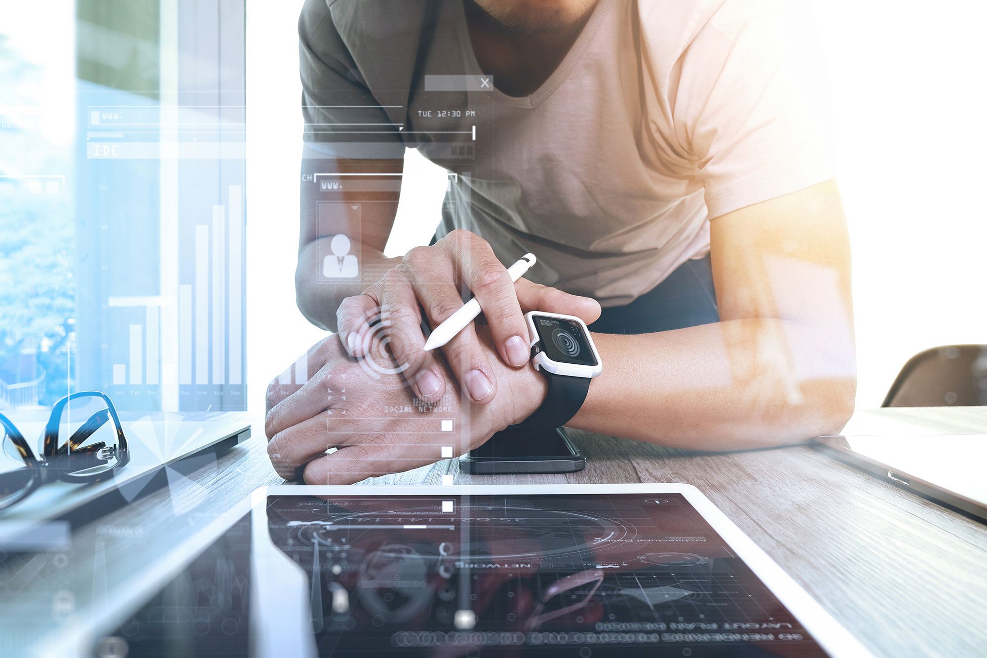 man wearing smart watch, leaning over desk looking at ipad
