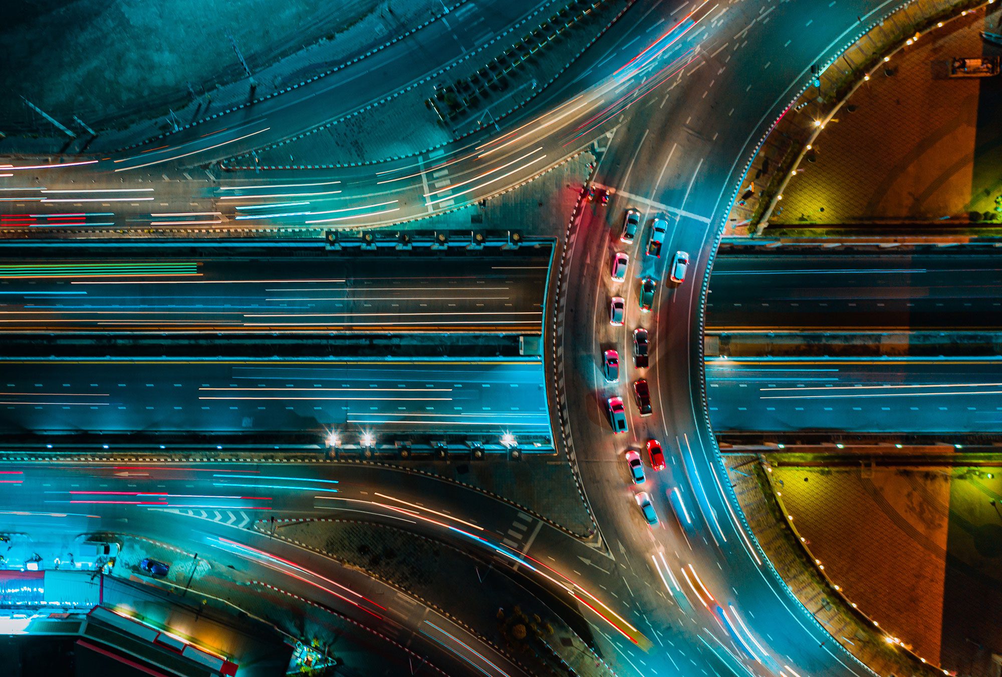 overhead view of colorful highway curve with cars at night