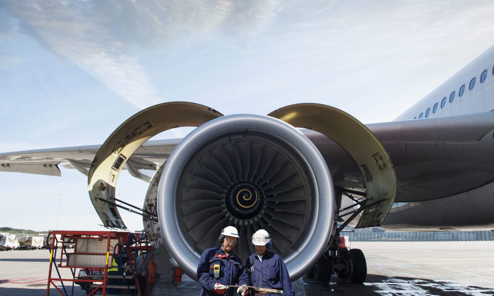 Aerospace engineers standing in front of turbine engine of aircraft on runway